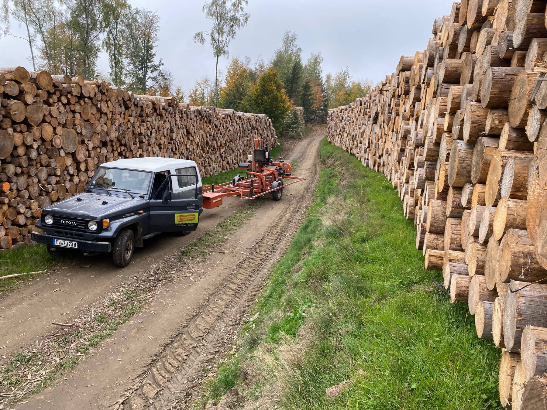 Stubbenfräse und Transportfahrzeug zwischen Holzstapeln